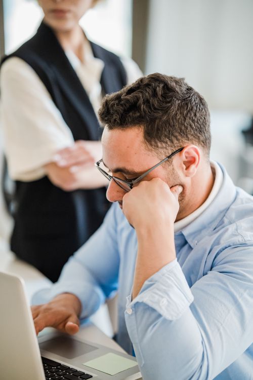 A man working at a laptop with a colleague nearby