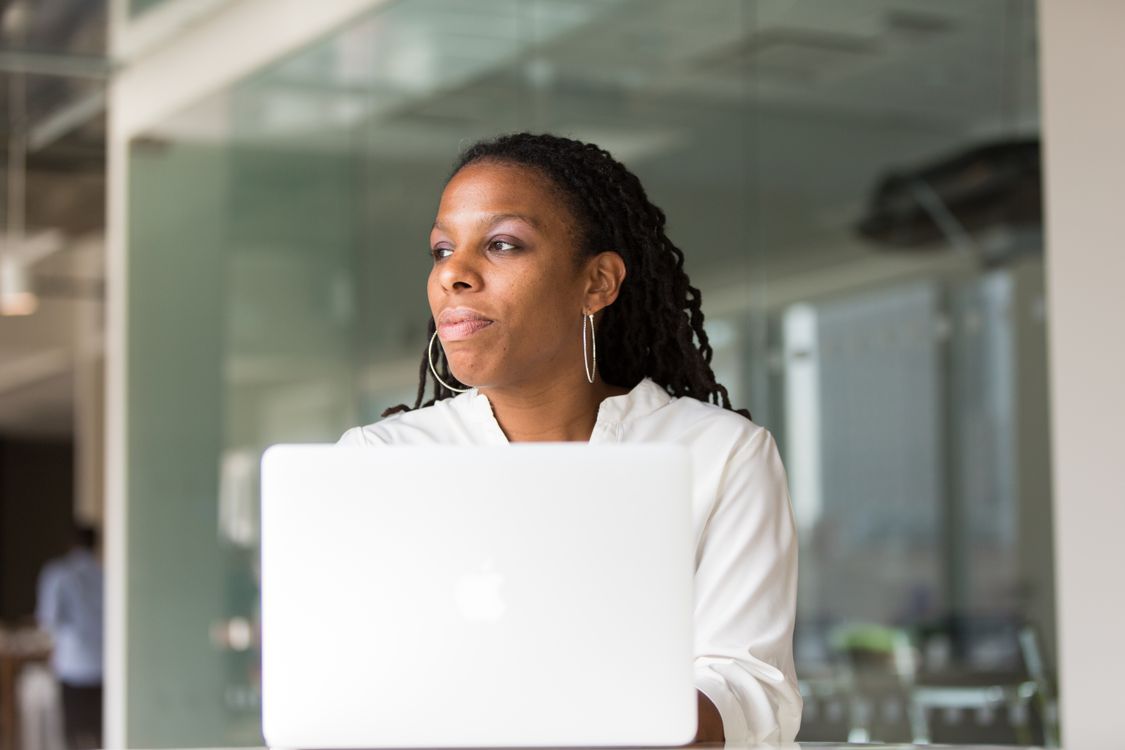 A person pausing beside her laptop at work